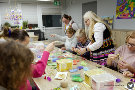 Uczestnicy pracują nad swoimi ozdobami. Prowadząca warsztaty pomaga jednej z uczestniczek.