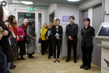 Obok Aleksandry Szulc-Chomy stoi mężczyzna ubrany w czarną koszulkę i czarną marynarkę. Obok niego stoi kobieta ubrana w czarną koszule z krótkim rękawem.