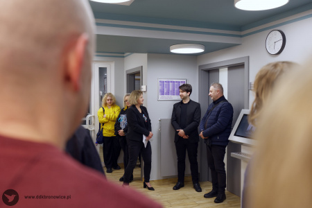 Po lewej stronie rozmyte kontury mężczyzny. Po prawej stronie Aleksandra Szulc-Choma przemawia do uczestników wystawy.