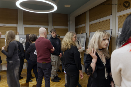 Grupa uczestników ogląda wystawę linorytów.