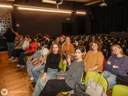 Uczestniczki i uczestnicy siedzą w sali teatralnej w Pracowniach Kultury Maki.