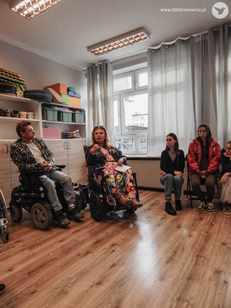 Kobieta i mężczyzna na wózku inwalidzkim. Obok siedzą uczestnicy. Przemawia kobieta na wózku.