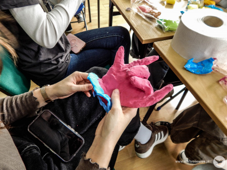 Uczestniczka tworzy rzeźbę dłoni. Jest koloru fioletowego i niebieskiego.