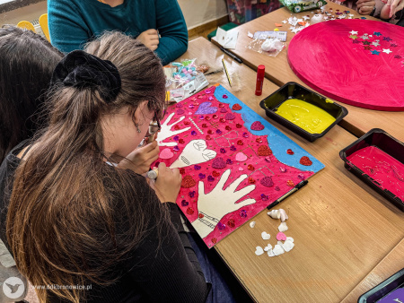 Uczestniczki tworzą obraz. Jest różowo-błękitny. Widać na nim białe ręce i białą głowę w kształcie serca.