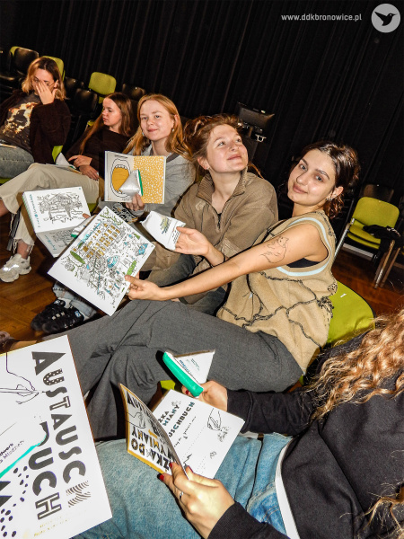 Pracownie Kultury Maki. Sala teatralna. Uczestniczki siedzą na zielonych krzesłach. Trzymają w rękach książki.