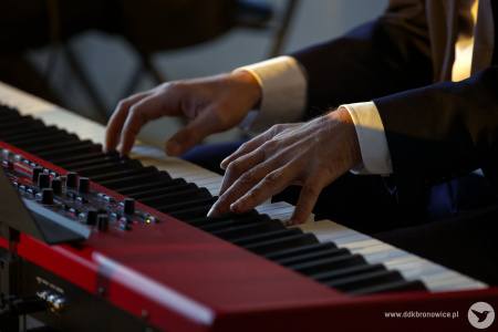 Czerwone pianino. Czarno-białe klawisze. Na pianinie gra Gabriel Menet.