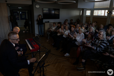 Po prawej stronie widownia jest uśmiechnięta. Klaszczą w dłonie. Po lewej stronie artyści przygotowują kolejny utwór.