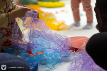 Niebieskie i fioletowe chusty leżą na białym dywanie.