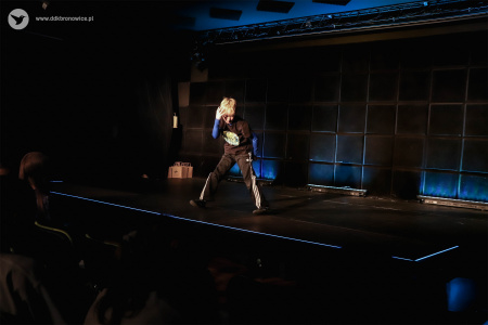 Scena podświetlona na niebiesko. Na scenie tańczy bardzo energicznie chłopiec.