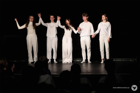 Aktorzy stoją na scenie. Trzymają się za ręce. Kłaniają się widowni.