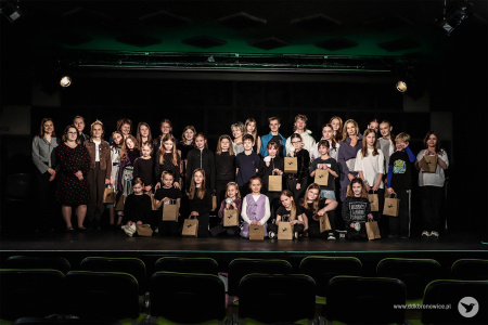 Zdjęcie wszystkich grup biorących udział w Przeglądzie. Uczestnicy i uczestniczki stoją na scenie. Uśmiechają się.