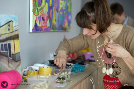 Kobieta w beżowym swetrze wybiera potrzebne materiały do stworzenia świątecznej ozdoby.