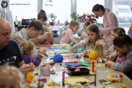 Stół warsztatowy. Na nim leży bardzo duża ilość materiałów artystycznych. Dzieci tworzą swoje kolorowe ozdoby.