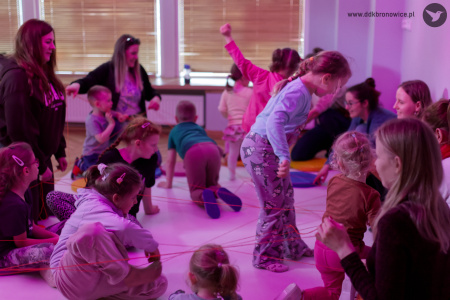 Dzieci bawią się czerwoną wstążką. Zapalone jest fioletowe światło.