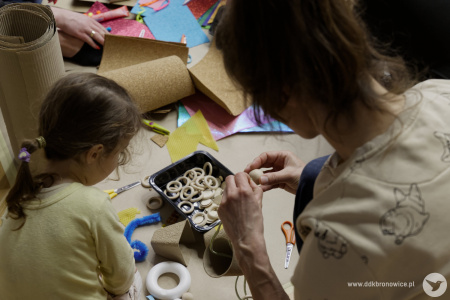 Mama pomaga dziewczynce w tworzeniu artystycznej ozdoby. Używają do tego tekturowych kubków i kolorowego papieru.