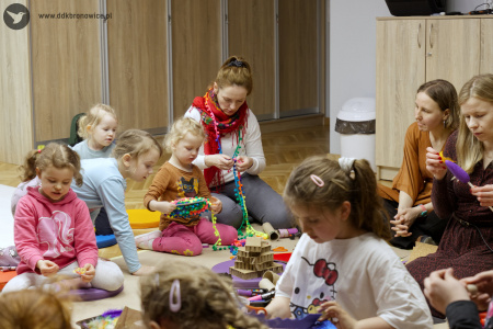 Grupa dzieci tworzą w skupieniu artystyczne ozdoby.