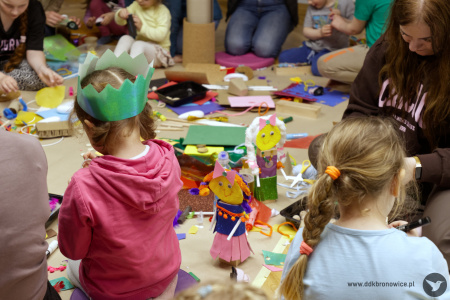 Dziewczynki tworzą swoje zabawki. Dziewczynka po lewej stronie ma założoną błękitną koronę.