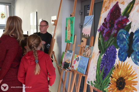 Po prawej stronie widać duży obraz. Przedstawia kwiaty i owady. W tle osoby oglądają wystawę w Galerii Małej.