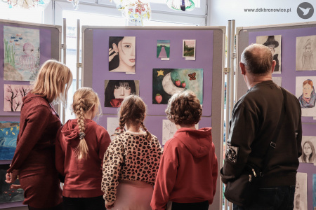 Trójka dzieci ogląda wystawę. Po prawej i po lewej stronie stoją dorośli.