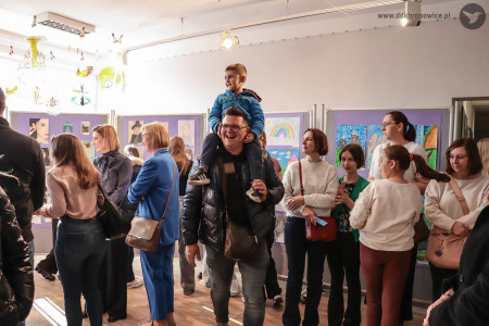 Na ramionach taty siedzi chłopiec w niebieskiej bluzie. Mężczyzna szeroko uśmiecha się.