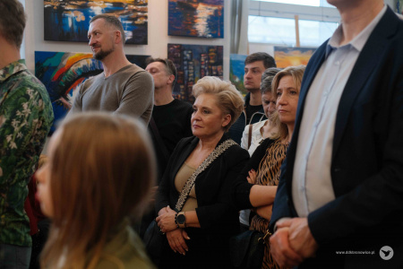 Grupa osób słucha przemówień.