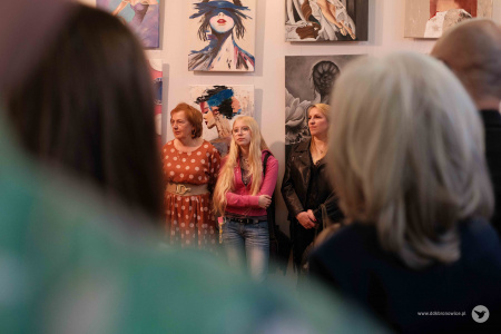 Uczestnicy grupy słuchają przemówień. W tle wiszące obrazy.