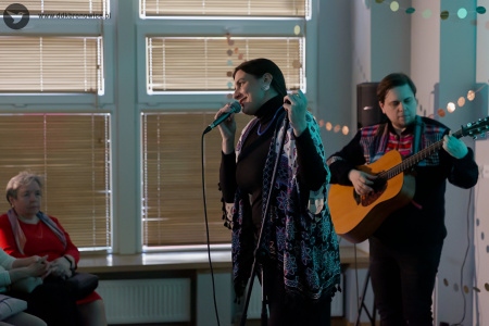 Wokalistka wykonuje emocjonalną piosenką. W tle gitarzysta grający na gitarze. Pada na nich błękitne światło.