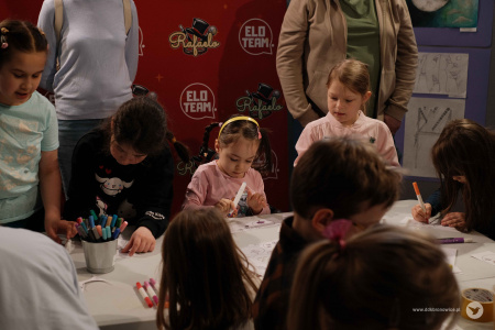 Pracownie Kultury Maki. Warsztaty przed spektaklem. Przy stole warsztatowym dzieci pracują nad papierowymi ozdobami.
