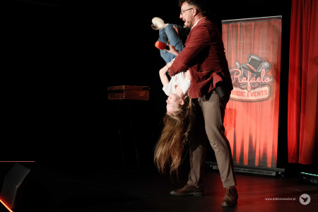 Magik podniósł dziewczynkę i odwraca ja do góry nogami. Dziewczynka śmieje się.