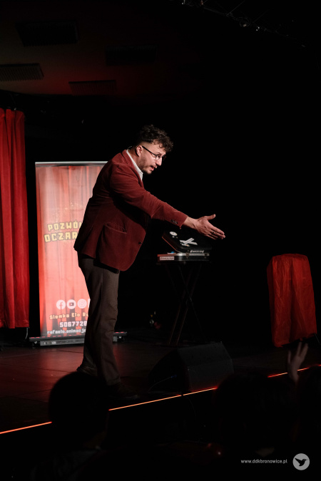 Magik w czerwonej marynarce zaprasza kolejną osobę na scenę.