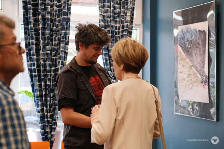 Jolanta Górajek-Jóźwik w białym żakiecie rozmawia z mężczyzną w czarnej koszuli.
