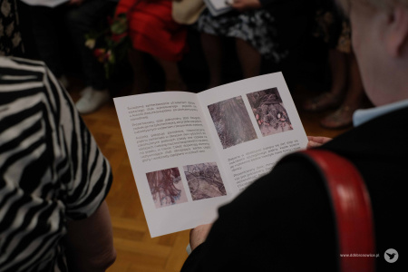 Uczestniczka wystawy przegląda folder dotyczący wystawy i obrazów.