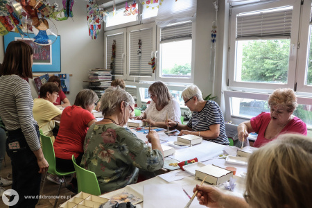 Seniorki pracują nad swoimi drewnianymi ozdobami.