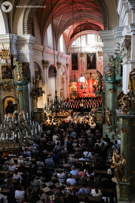 Widok z góry. W ławkach i rozłożonych krzesełkach siedzi zgromadzona publiczność.