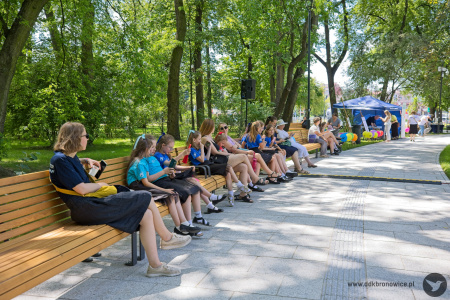 Na ławkach siedzą ludzie. W tle widać niebieski namiot Dzielnicowego Domu Kultury „Bronowice".