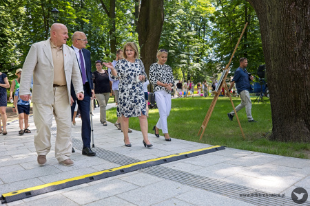 Spacer po parku. Na przodzie idzie Krzysztof Żuk, Jarosław Stawiarski i Aleksandra Szulc-Choma. Dookoła spacerują mieszkańcy.