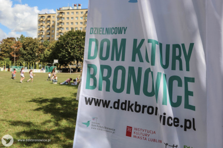 Flaga z napisem: Dzielnicowy Dom Kultury Bronowice. W tle bawiące się dzieci.