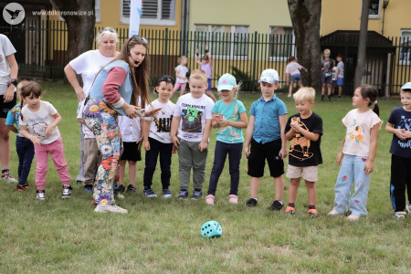 Prowadząca rozmawia z dziećmi. Obok nich leży duża niebieska kostka do gry.