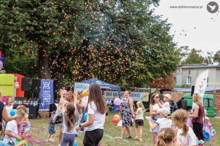 Dzieci i rodzice bawią się wystrzelonym confetti. Dzieci biegają i tańczą.