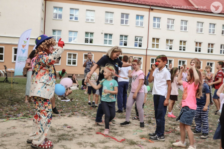 Dyrektor Aleksandra Szulc-Choma tańczy z grupką dzieci. Obok nich stoi klaun w niebieskim meloniku.