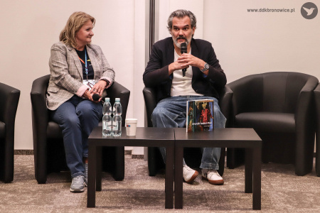 Po lewej dyrektor Dzielnicowego Domu Kultury Bronowice Aleksandra Szulc-Choma, po prawej autor książki Marcin Wąsowski. Siedzą na czarnych fotelach. Na przeciwko nich czarny stolik. Na nim woda i książki,