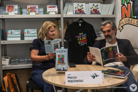 Na stoisku DDK Bronowice Marcin Wąsowski czyta fragmenty książki: Kroniki Babci Poli. Obok niej siedzi Aleksandra Szulc-choma.