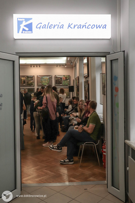 Wejście do Galerii Krańcowej. Nad przeszklonymi drzwiami podświetlony napis: Galeria Krańcowa. Widać w galerii bardzo dużo osób.