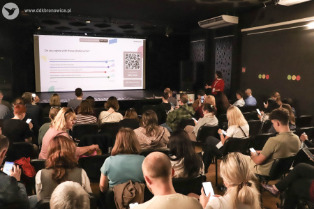 Uczestnicy TRIYOU Forum oglądają załączoną prezentację. Obok stoi prowadzącego tego panelu Marta Gawinek-Dagargulia.