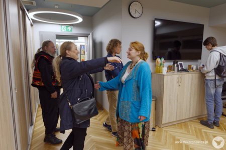 Koordynatorka Galerii Przechodniej Emilia Skubis wita się z uczestniczką wystawy ubraną w kurtkę.