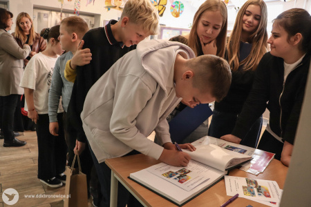 Uczniowie, uczennice i nauczyciele wpisują się do pamiątkowej Księgi Gości Galerii Małej.