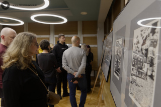 Grafika promująca wystawę prac graficznych w Pracowniach Kultury Dziesiąta w Galerii Przechodniej. Na białym tle, po prawej stronie grafiki fragment linorytu. Przedstawia Bramę Trynitarską w Lublinie. Grafika jest czarno-biała. W lewym górnym rogu logotyp Galerii Przechodniej: ciemnoszary prześwit z białymi liniami. Pod nim czarny napis: “GALERIA PRZECHODNIA”. W lewym dolnym rogu mały koliber na szarym tle, obok napis: www.ddkbronowice.pl.